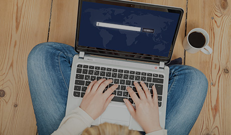 AlphaNumerique : Photo d'un ordinateur portable avec des mains qui tapent sur le clavier avec une barre de recherche Web incrustée.